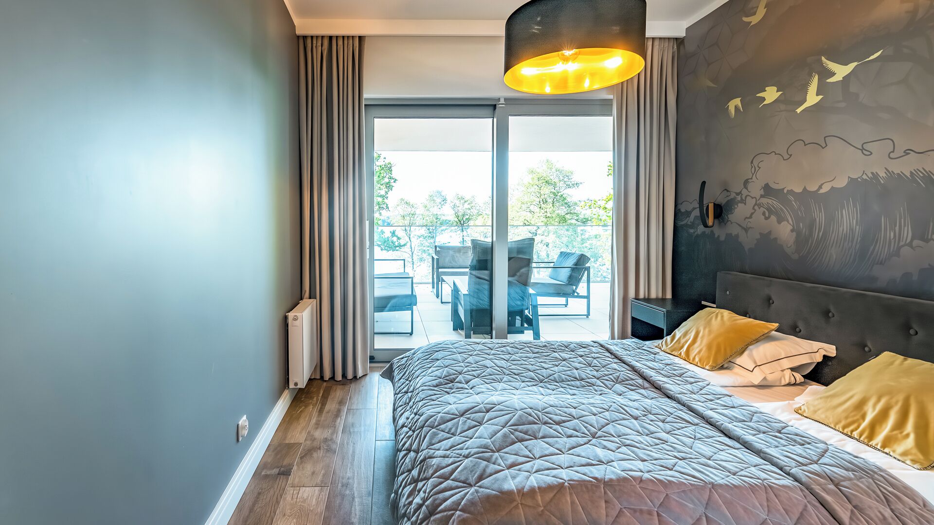 A modern bedroom with a large bed, a view of the outdoors, and a unique wall design.