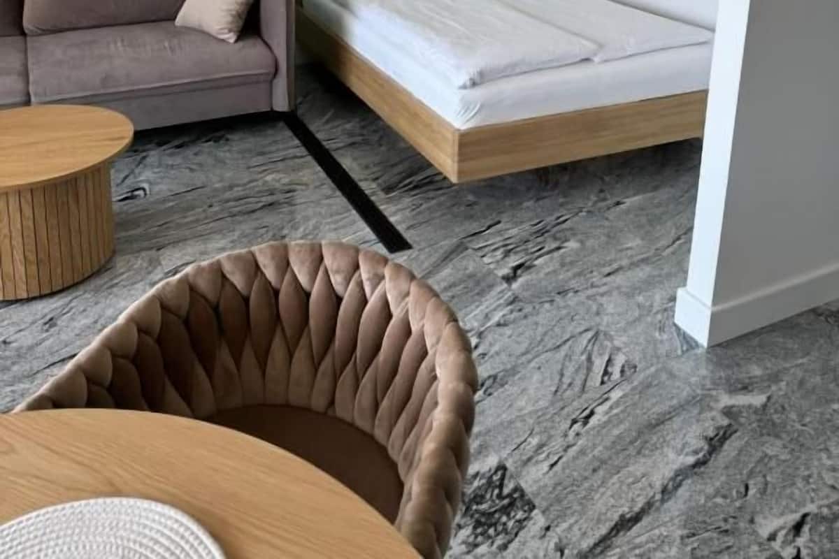 A modern room with a sofa, a bed, a round coffee table, and a cushioned chair.
