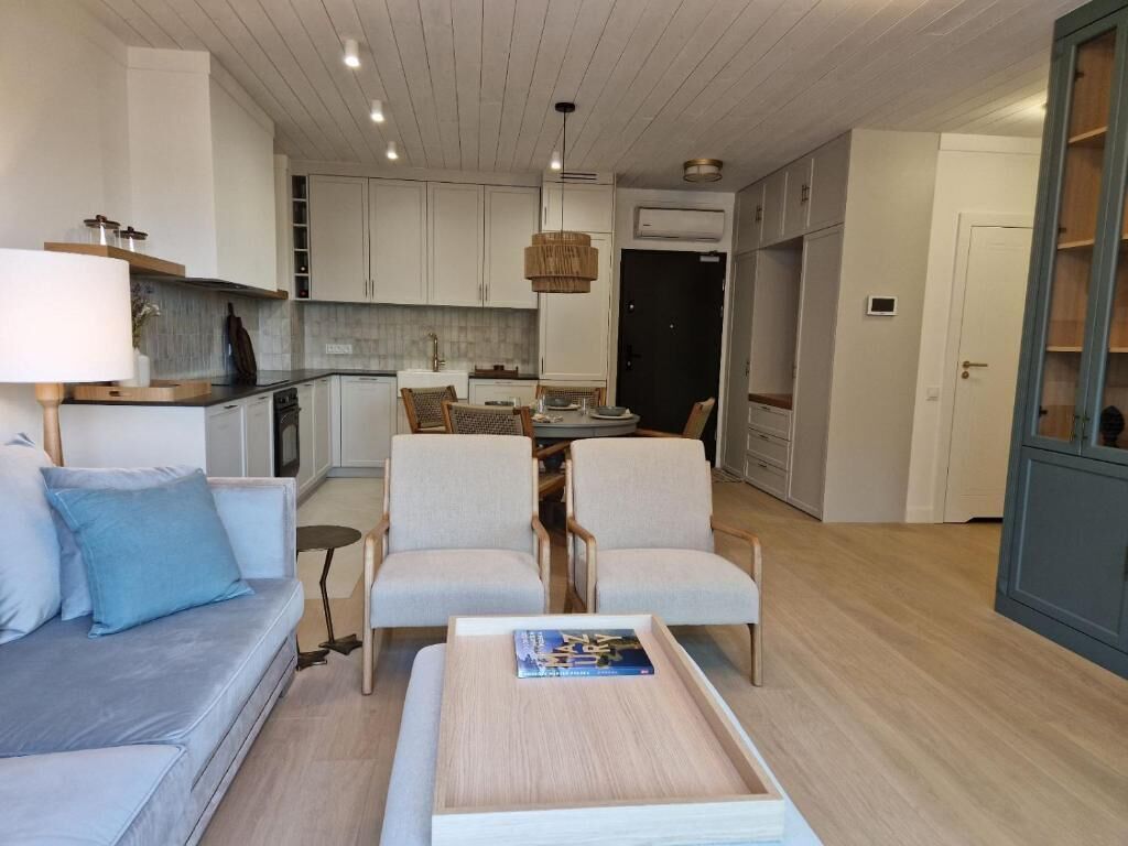 Een moderne woonkamer met een bank, stoelen, een salontafel en een eethoek met een tafel en stoelen.