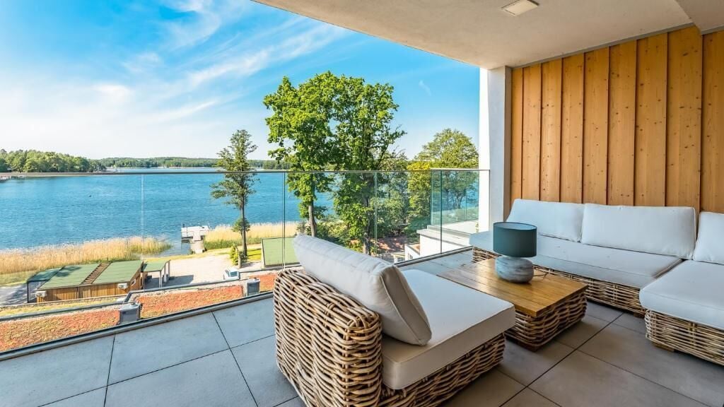 A balcony with wicker furniture, a white sofa, and a table with a lamp.
