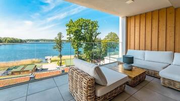 Ein Balkon mit Korbmöbeln, einem weißen Sofa und einem Tisch mit einer Lampe.