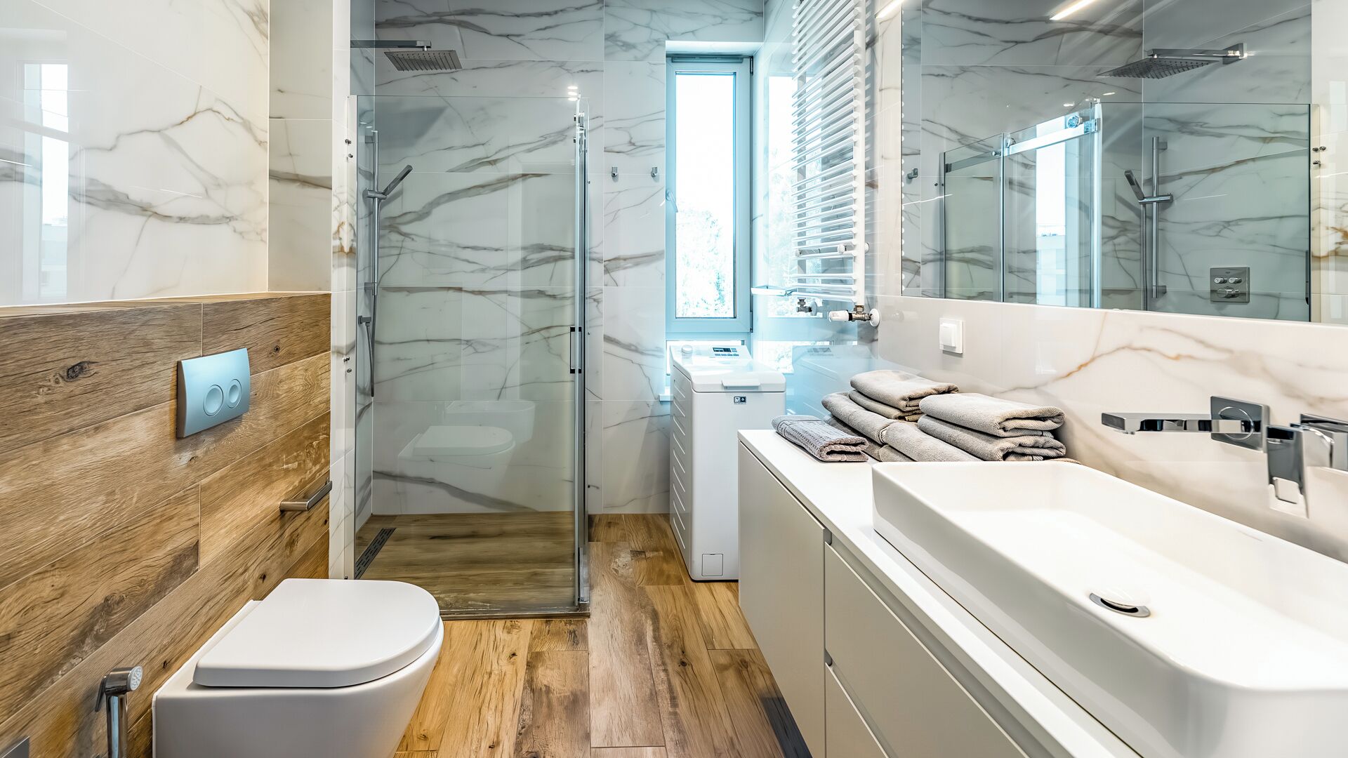 Ein modernes Badezimmer mit einer Duschkabine aus Glas, einem Holzwaschtisch und einer weißen Toilette.