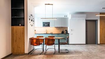 Una cocina moderna con comedor, que incluye un armario de madera, un reloj, un microondas y un refrigerador.