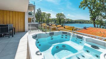 A hot tub on a balcony with a view of a lake and trees.