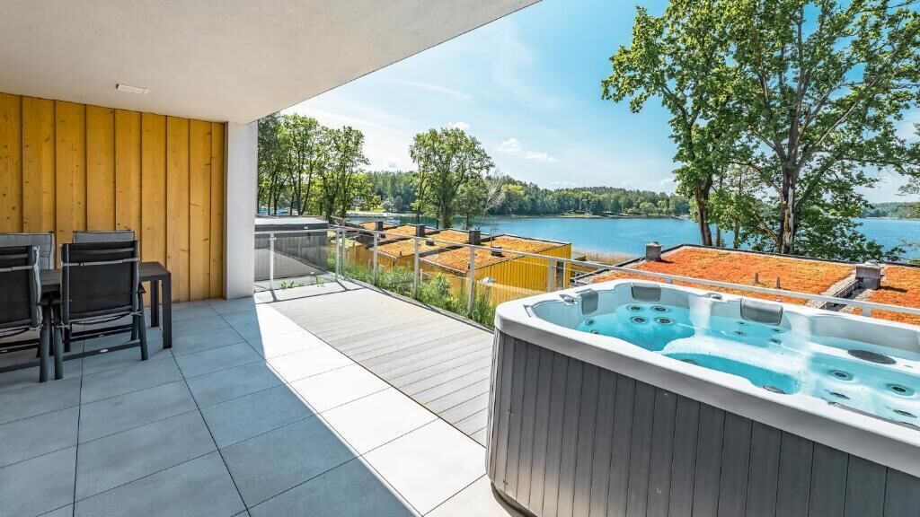 Un balcone con vasca idromassaggio, arredi da esterno e vista sul lago.