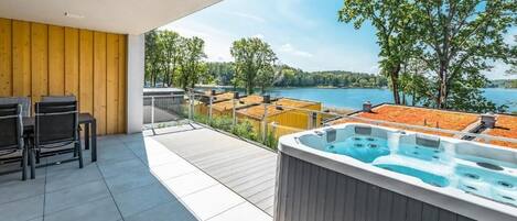 Un balcone con vasca idromassaggio, arredi da esterno e vista sul lago.