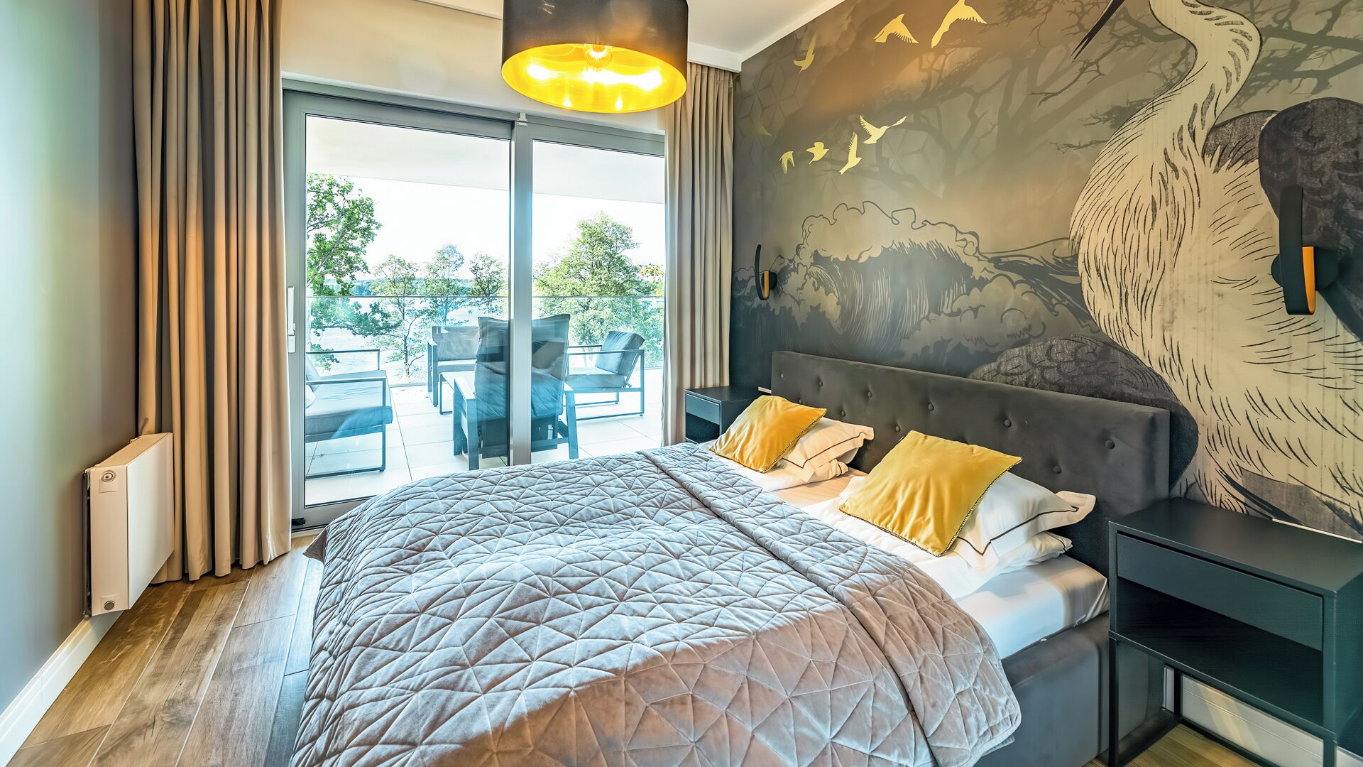 A bedroom with a large bed, a view of the outdoors, and a mural on the wall.