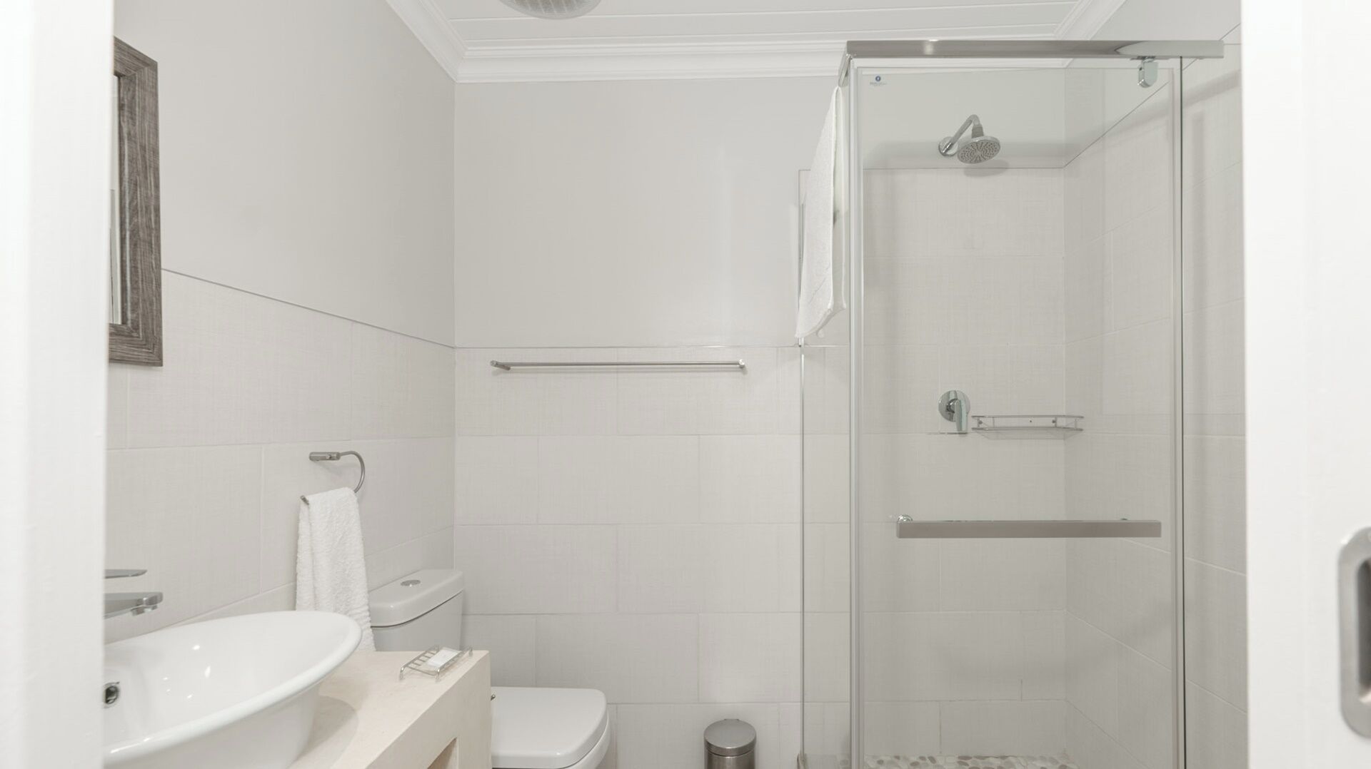 A bathroom with a shower, toilet, sink, and towel rack.