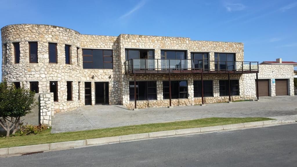 A modern building with a stone facade, multiple windows, and a balcony.