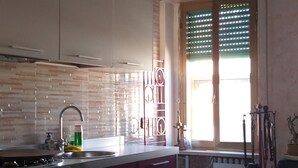 Una cocina con una isla central, una mesa de comedor con sillas y una ventana con persianas.