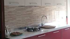 Una cocina moderna con armarios blancos, una encimera roja y salpicadero.