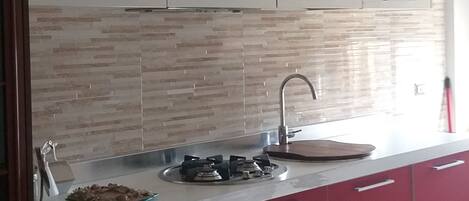 Una cocina moderna con armarios blancos, una encimera roja y salpicadero.