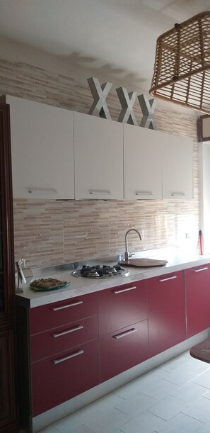 Una cocina moderna con armarios blancos, una encimera roja y salpicadero.