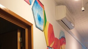 Un pasillo con arte abstracto de colores en la pared, una puerta de madera y un equipo de aire acondicionado.