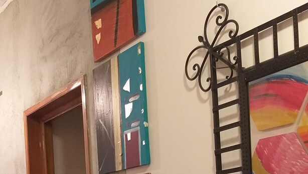 Un pasillo con puerta de madera, suelo de baldosas y una pared decorada con arte abstracto.