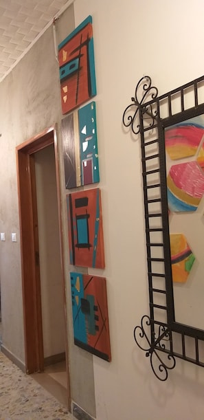 Un pasillo con puerta de madera, suelo de baldosas y una pared decorada con arte abstracto.