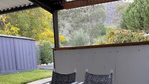Eine überdachte Terrasse mit Tisch und vier Stühlen, jeweils mit gemusterten Kissen.