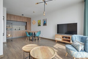 A modern living room with a dining area, a TV, and a kitchen in the background. - Św. Barbary 161 by Grand Apartments (Gdańsk)