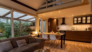 A modern kitchen with a dining area, large windows, and a cozy seating area with a sofa and coffee table. - Real Zeeland tranquility within walking distance of the Oosterschelde estuary (Stavenisse)