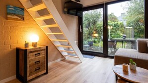 A modern interior with a staircase, a sofa, a coffee table, and a view of the outdoors. - Real Zeeland tranquility within walking distance of the Oosterschelde estuary (Stavenisse)