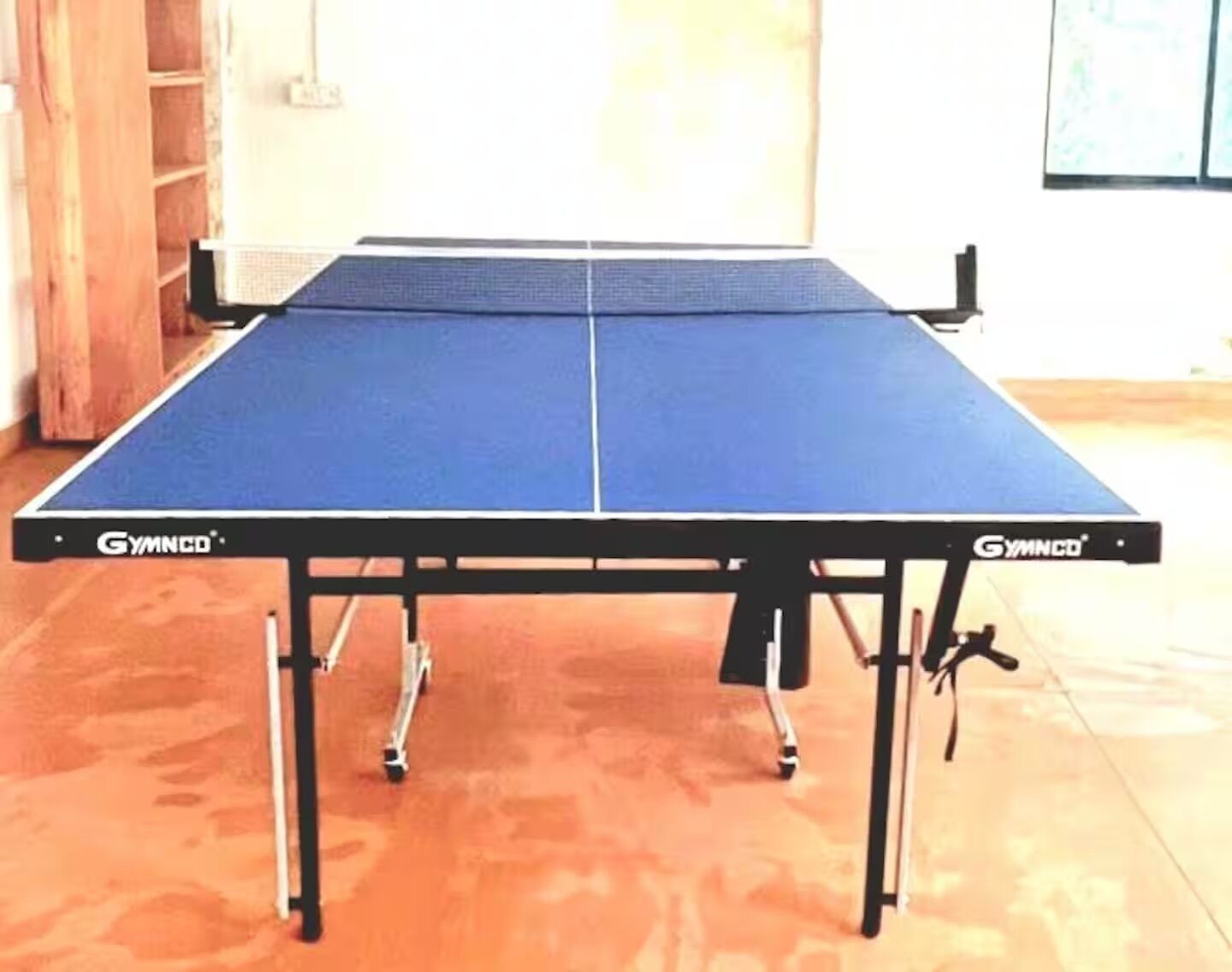 A table tennis table with a blue playing surface and black net.