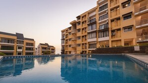 Un edificio residencial de varios pisos con una piscina en primer plano.
