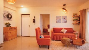 Una sala de estar con un sofá, un sillón, un aparador de madera y un ventilador de techo.
