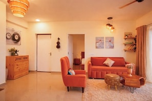 Un salon comprenant un canapé, un fauteuil, un meuble en bois et un ventilateur de plafond.