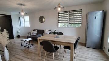 A modern kitchen with a dining table, chairs, a refrigerator, and a window with blinds.