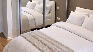 Ein Schlafzimmer mit einem großen Bett, einem Spiegel und einem Sessel.