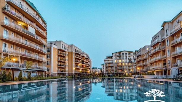 Ein mehrstöckiges Hotel mit Balkonen, einem Swimmingpool und blauem Himmel.