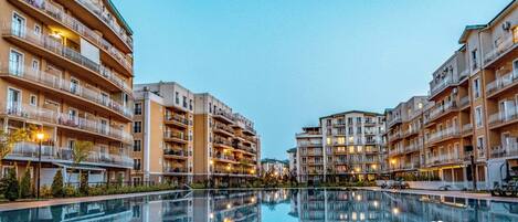 Un hotel de varios pisos con balcones, piscina y cielo despejado.