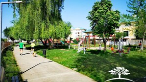 Ein Park mit befestigtem Weg, Spielgeräten und Bäumen.