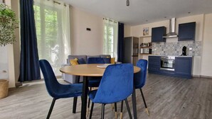 Une cuisine moderne avec des armoires bleues, un four encastré et un coin repas comprenant une table ronde et des chaises bleues.