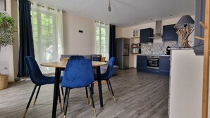 Une cuisine moderne avec des meubles bleus, un four à micro-ondes et une cuisinière. On y trouve également un coin repas avec une table ronde et des chaises bleues.