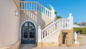 Ein mehrgeschossiges Gebäude mit einer Steintreppe, einem Bogenportal und einem Balkon.