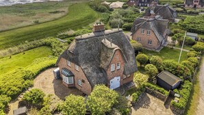 A coastal village with traditional thatched-roof cottages, a sandy beach, and a clear view of the sea.