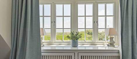 A room with a bay window, a radiator, and a potted plant.