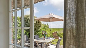An open patio with a table, chairs, a table umbrella, and a view of the countryside.
