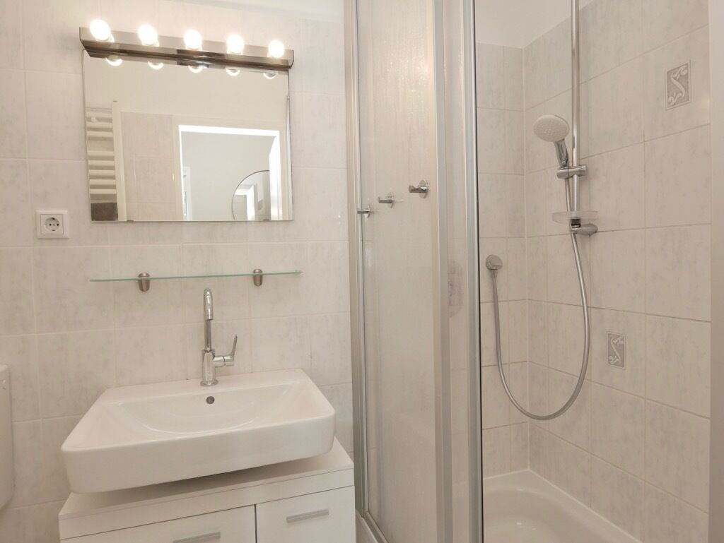 Une salle de bain avec un lavabo, un miroir et une douche.
