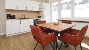 Una cocina moderna con armarios blancos, una mesa de madera y sillas rojas.