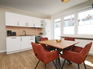 Eine moderne Küche mit weißen Schränken, einem Holztisch und roten Stühlen.