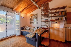A living room with a sofa, a bookshelf, and a window with a view of the outside. - The Landscape Home (Roma)