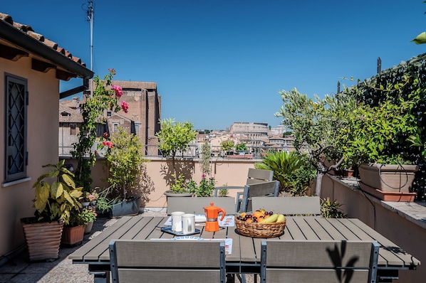 A terrace with a table set for breakfast, potted plants, and a view of historic buildings. - The Landscape Home (Roma)