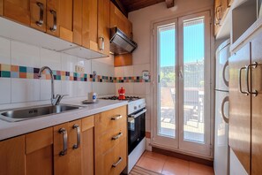 A kitchen with wooden cabinets, a stainless steel sink, a gas stove, and a built-in oven. - The Landscape Home (Roma)