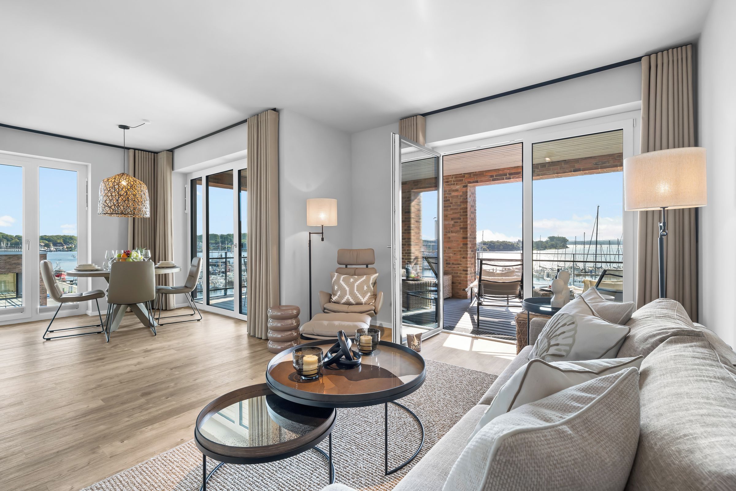 A spacious living area with a large window, a dining table with chairs, a sofa, and a coffee table.