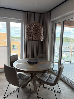 A modern dining area with a round table, four chairs, and a decorative hanging light fixture.