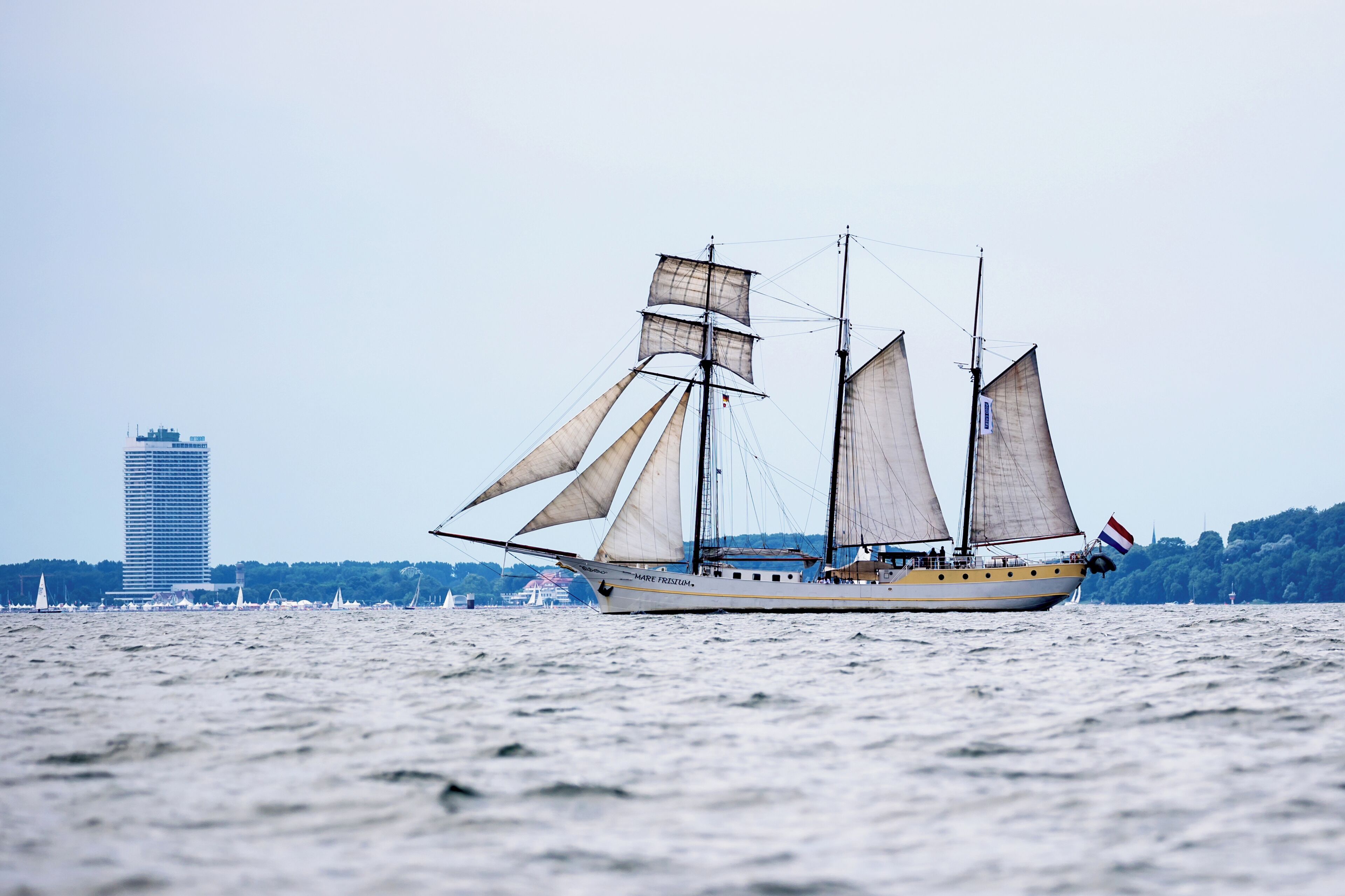 Un grand voilier à plusieurs voiles naviguant sur une étendue d’eau.