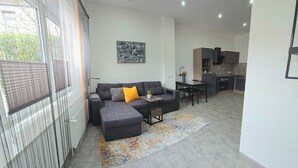 Ein modernes Wohnzimmer mit einer Eckcouch, einem Esstisch und einer Küchenzeile.