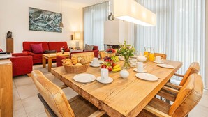 Un comedor con mesa de madera dispuesta para el desayuno, sofás rojos y un cuadro en la pared.